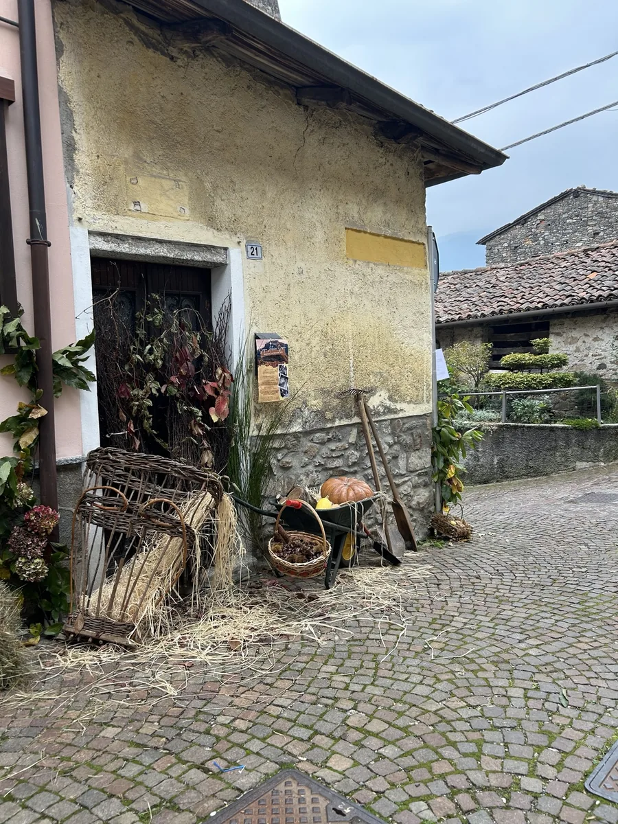 Allestimento tradizionale con gerla, paglia, castagne e zucca in una via di Parlasco